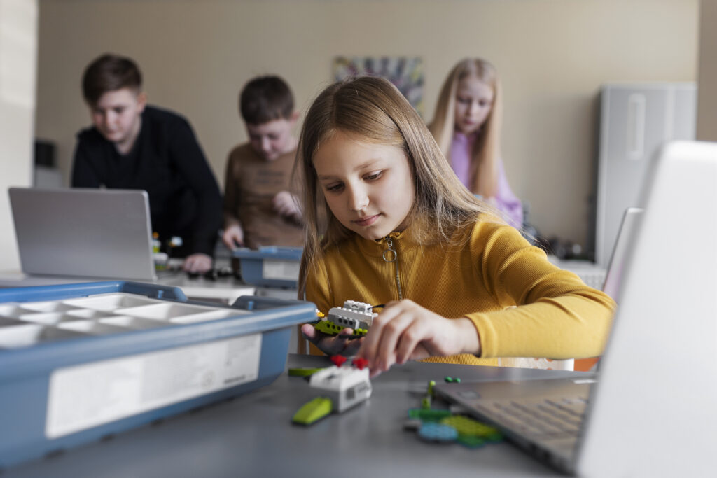 young-girl-using-laptop-electronic-parts-build-robot